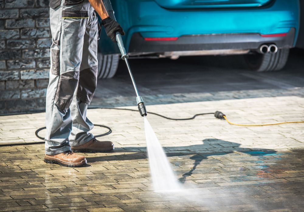 Professional Worker Cleaning Garage Using Pressure Washing