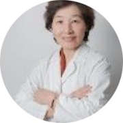 身穿白色實驗服、雙臂交叉、面帶微笑的女子，以白色為背景，並置於圓形相框內。