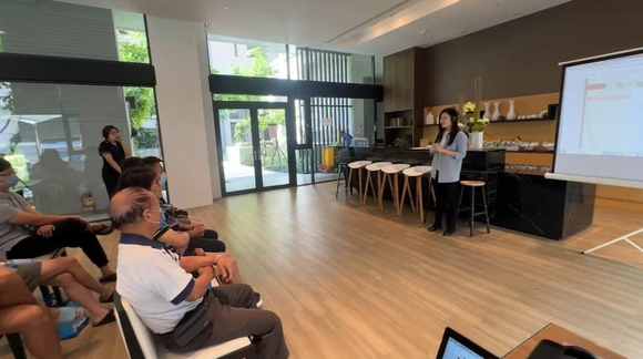 詠華地政士事務所所長-鄭秀慧女士在現代化的會議空間裡,透過投影螢幕向就座的觀眾講解地政相關知識。