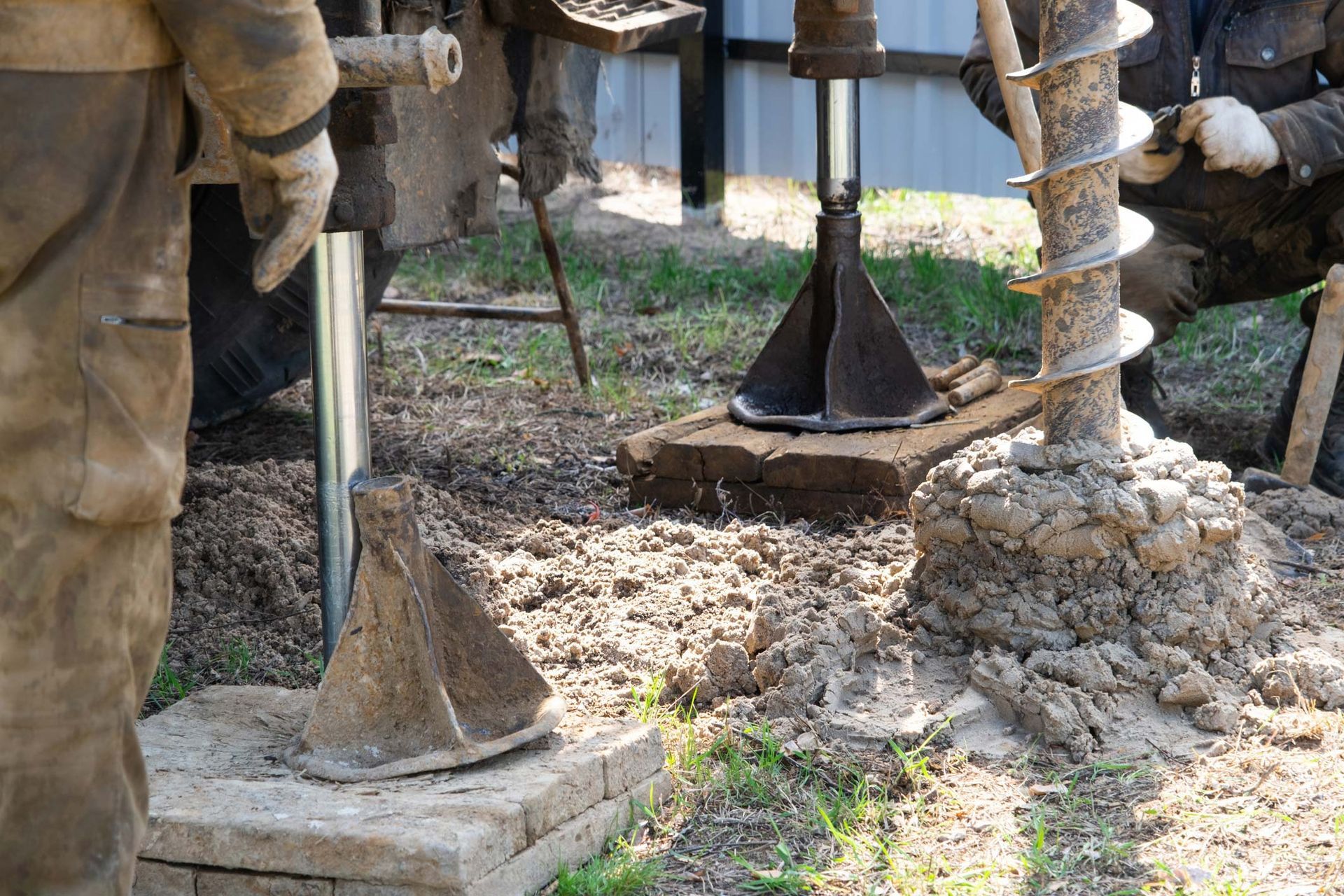 Workers drilling soil using auger equipment for a foundation project by a hwater well contractor.