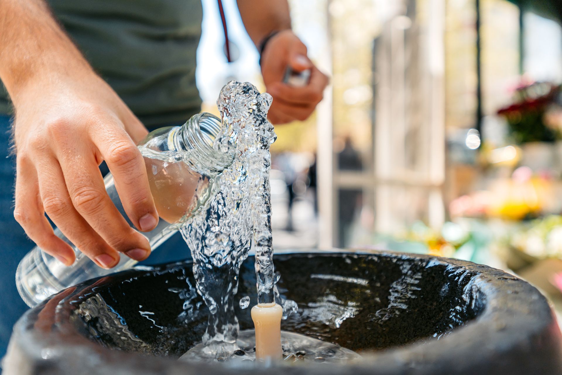 A man filling bottle at public fountain with help from a local water well contractor.