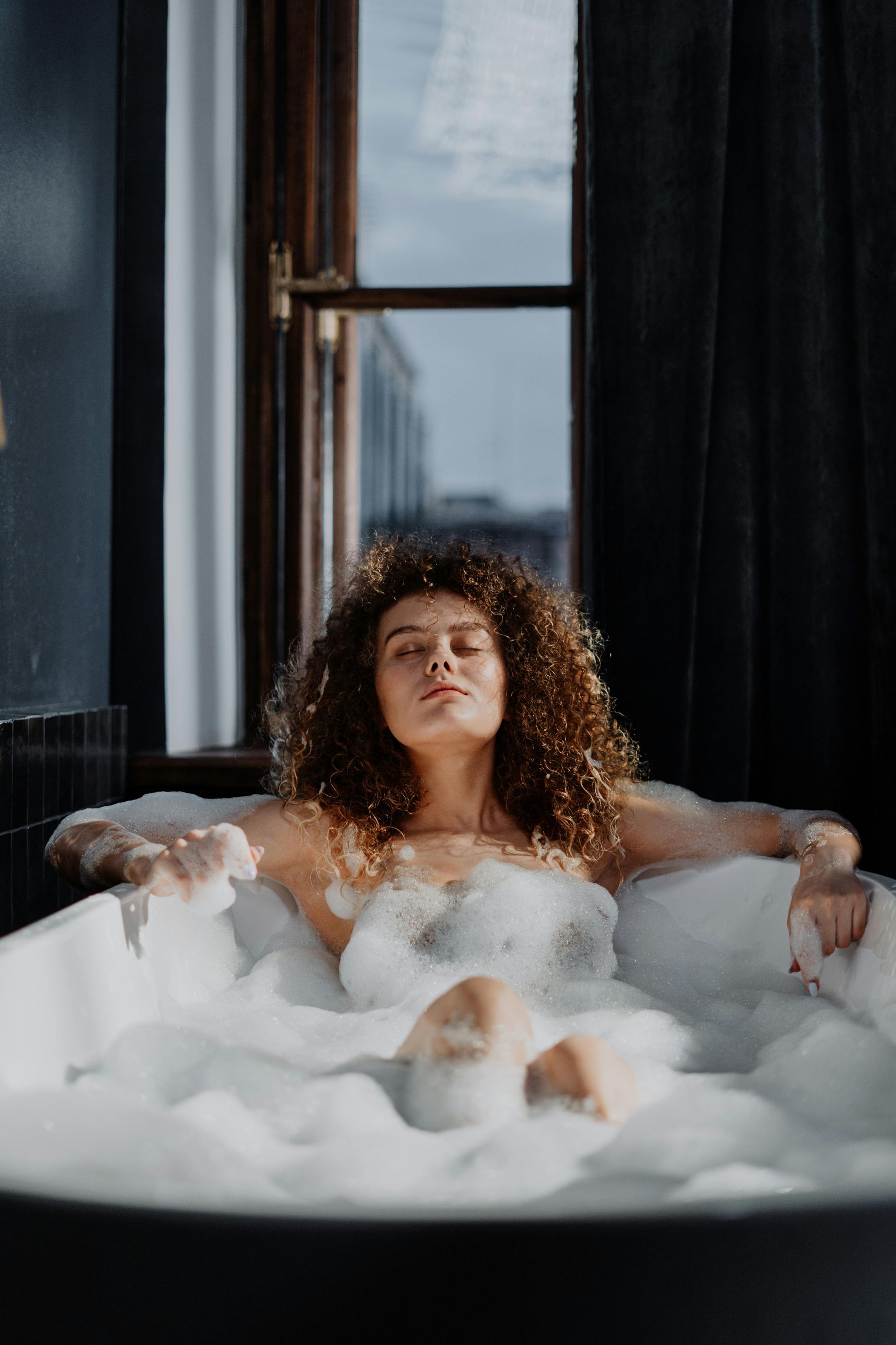 A woman is taking a bath in a bathtub filled with foam.