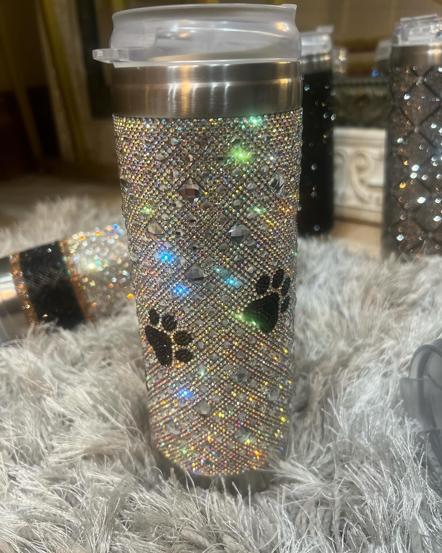 A stainless steel tumbler with rhinestones and a paw print on it.