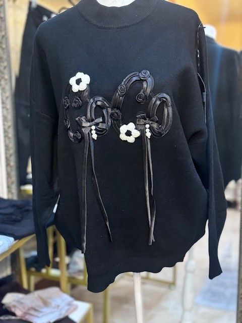 A black sweater with flowers on it is on a mannequin