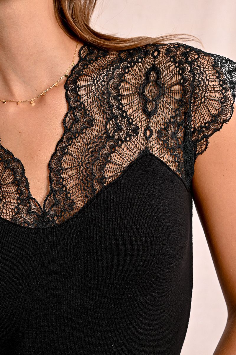A woman is wearing a black lace top with short sleeves.