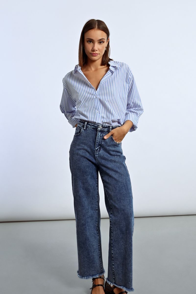 A woman is wearing a striped shirt and wide leg jeans.