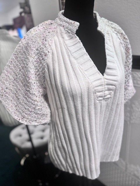 A white sweater with lace sleeves is on a mannequin.