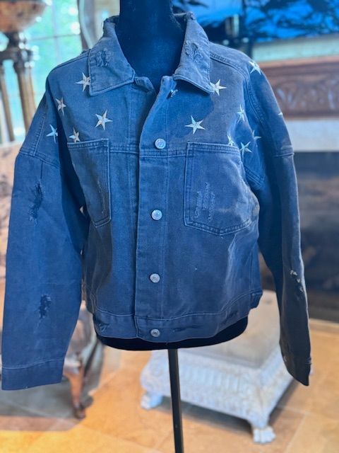 A blue denim jacket with white stars on it is on a mannequin.
