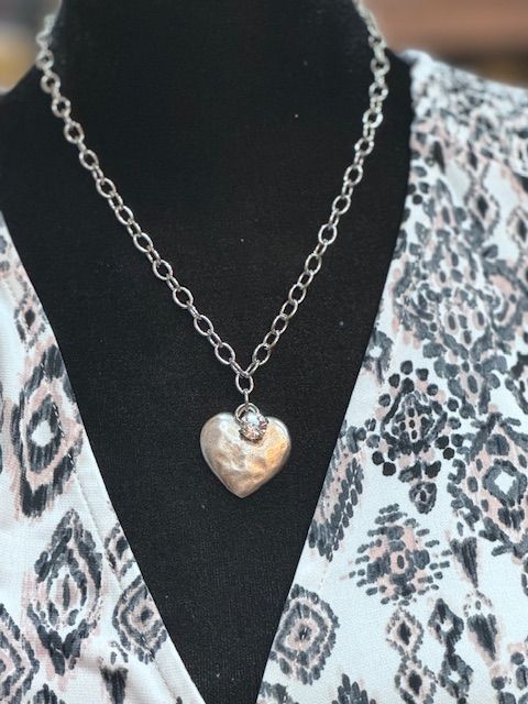 A woman wearing a necklace with a heart shaped pendant