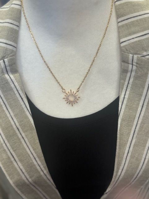 A woman wearing a necklace with a sun shaped pendant