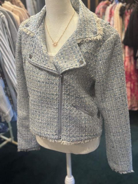 A mannequin is wearing a light blue jacket and a gold necklace.