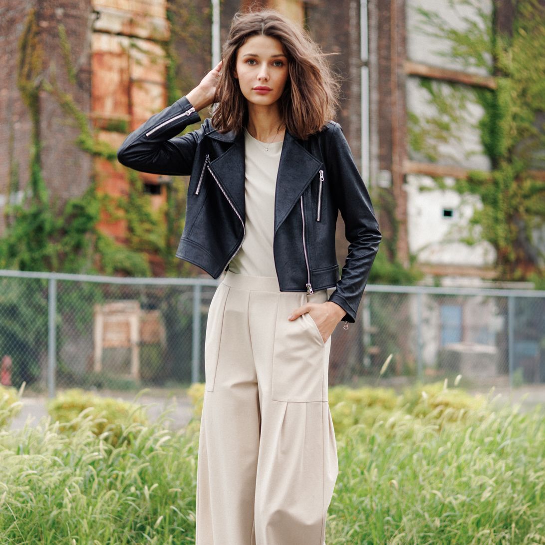 A woman wearing a black leather jacket and wide leg pants