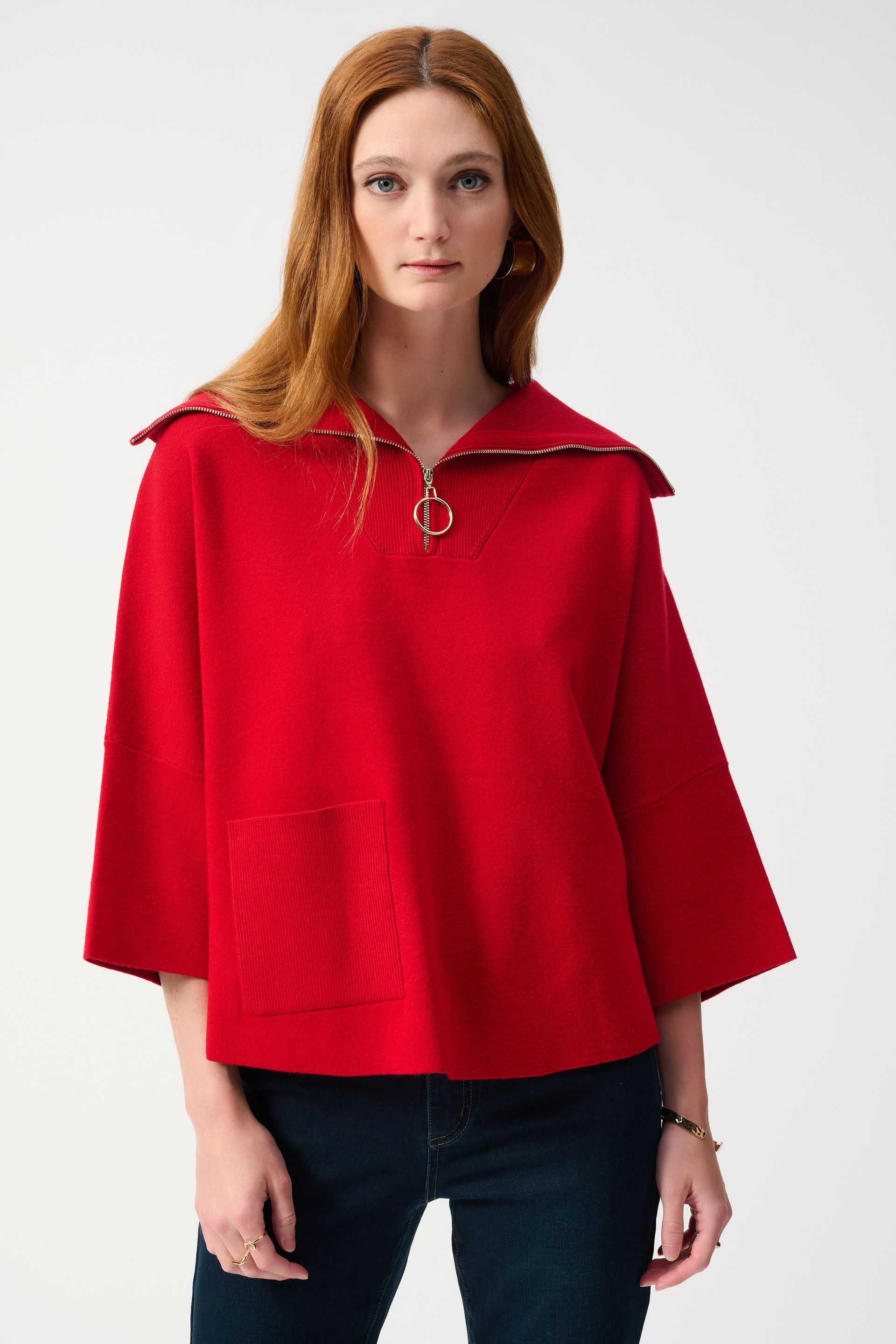 A woman is wearing a red sweater with a zipper on the front.