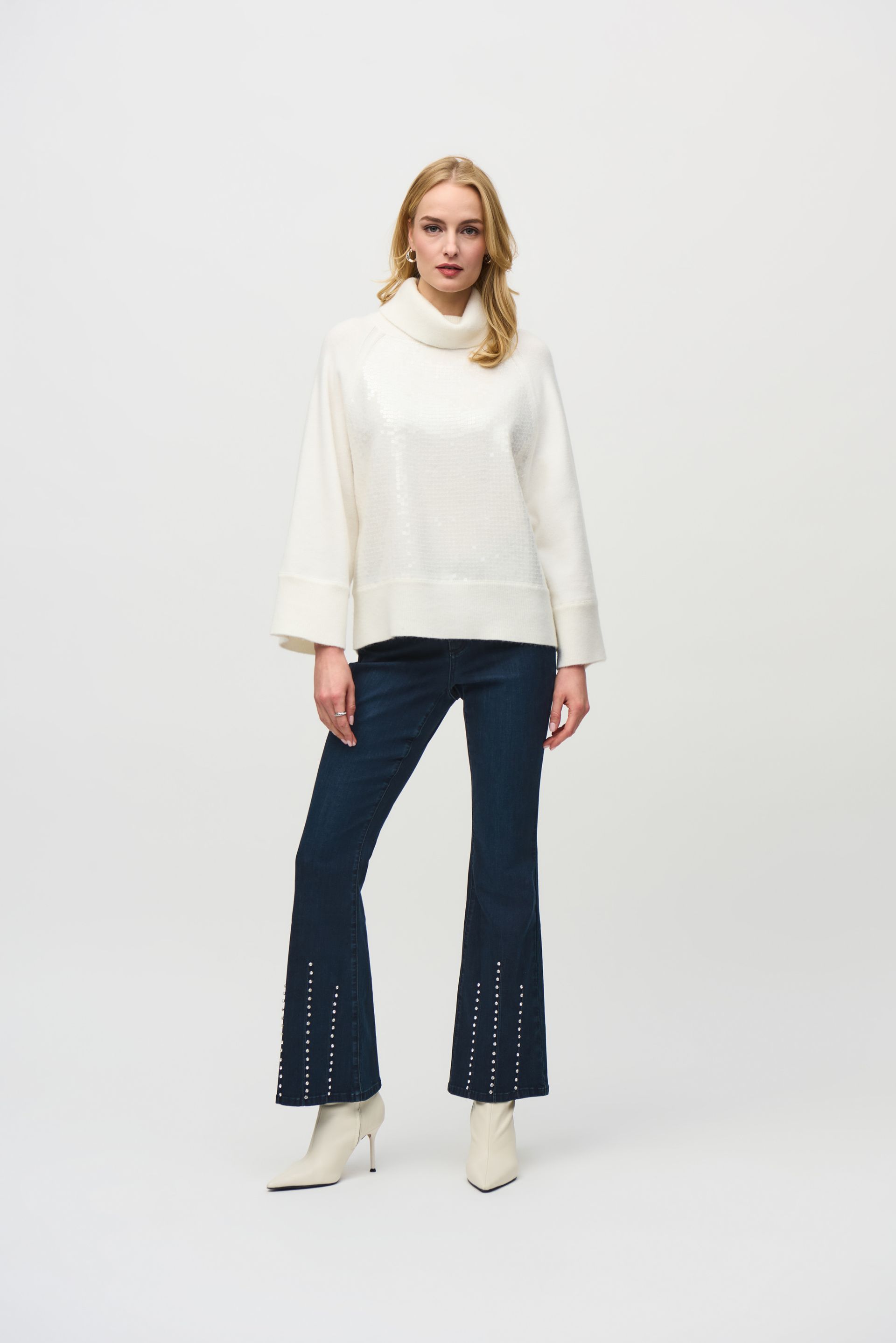 A woman is wearing a white sweater and blue jeans.