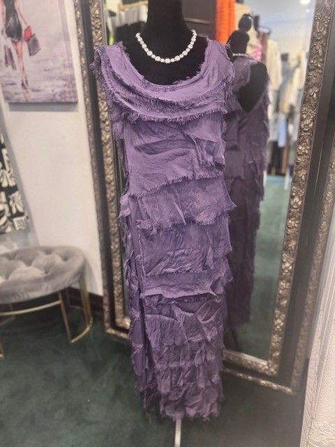 A purple dress is on a mannequin in front of a mirror.