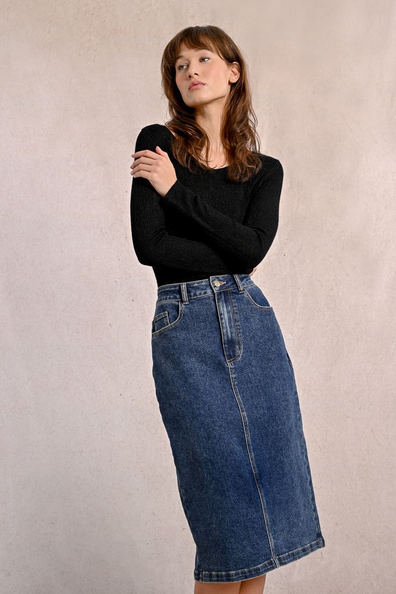 A woman is wearing a black top and a blue denim skirt.