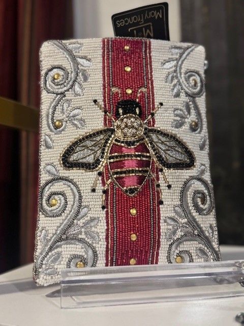 A painting of a bee with a red ribbon on a table.