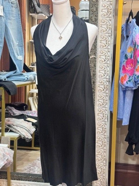 A black dress is on a mannequin in front of a mirror