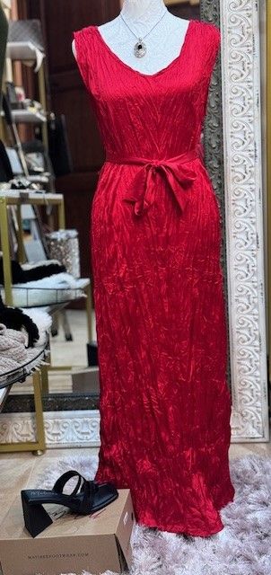 A red dress is on a mannequin in a store.