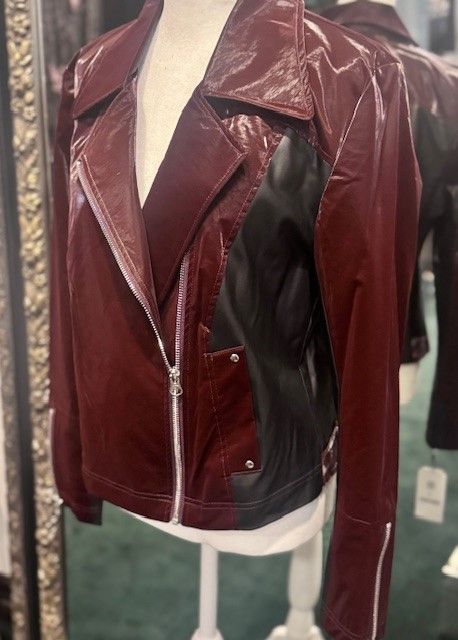 A red leather jacket is on a mannequin in front of a mirror.