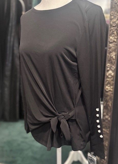 A black shirt with pearls on the sleeves is on a mannequin