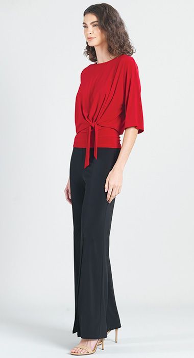 A woman is wearing a red top and black pants.
