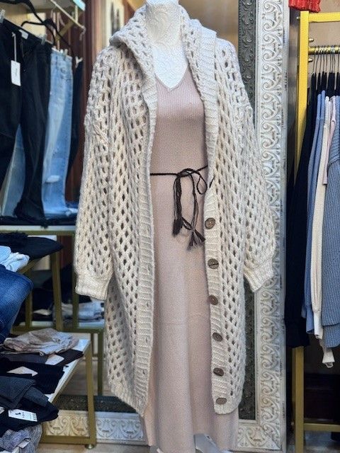 A mannequin wearing a white cardigan and a pink dress