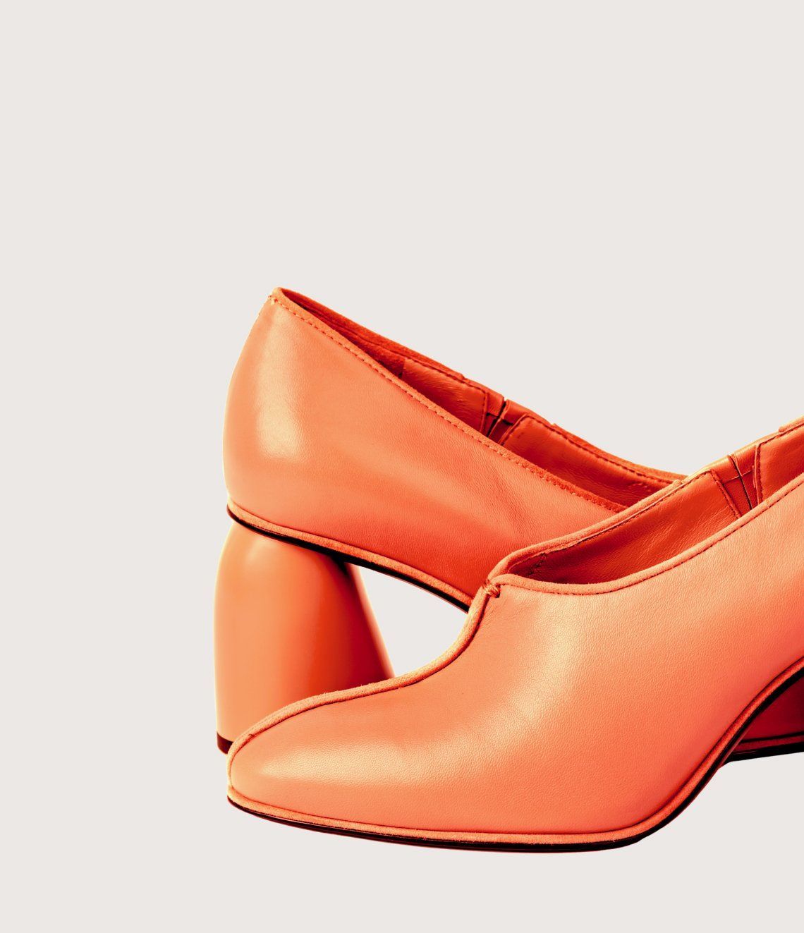 A pair of orange shoes with a block heel on a white background.