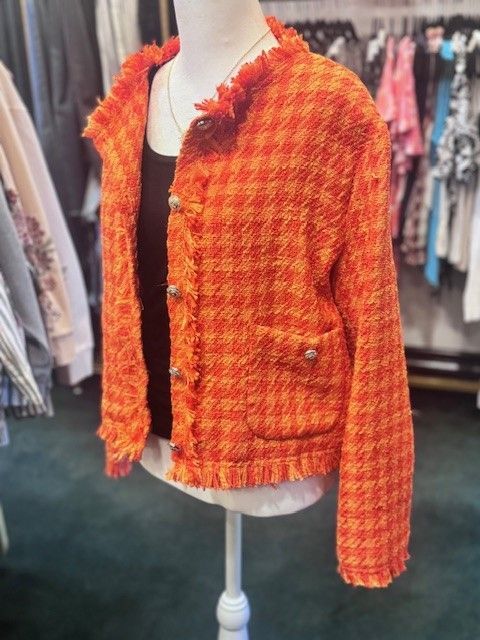An orange jacket is on a mannequin in a store.
