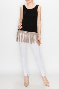A woman is wearing a black tank top and white pants with fringe.