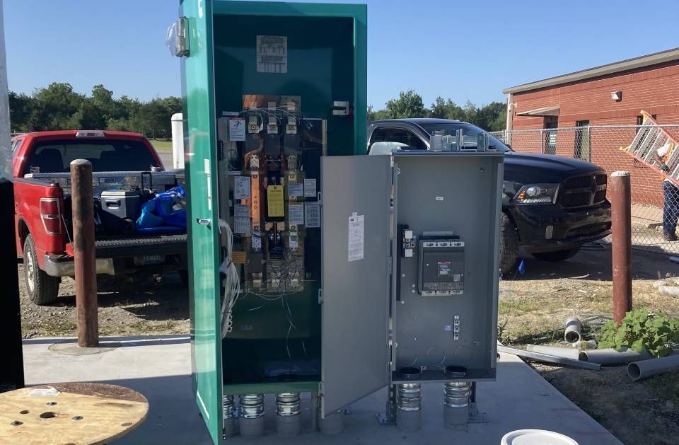 A green box is sitting on a sidewalk next to a red truck.