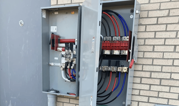 A electrical box is sitting on a brick wall.