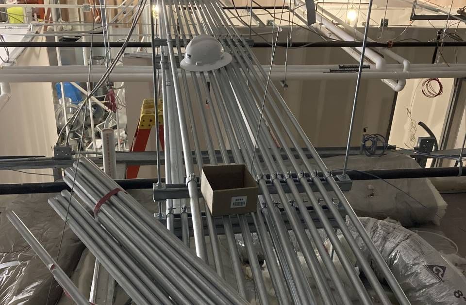 A hard hat is sitting on top of a pile of metal pipes.