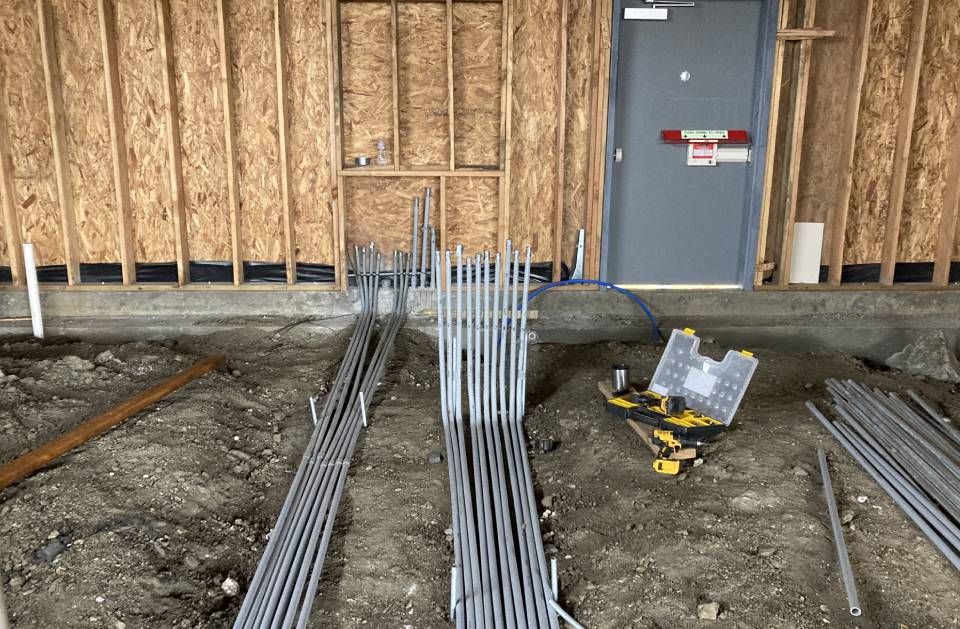 A bunch of metal pipes are sitting on the ground in front of a building under construction.