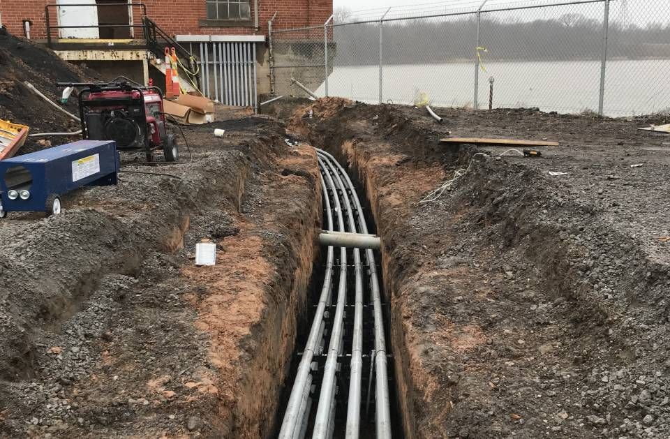 A bunch of pipes are being installed in a trench.