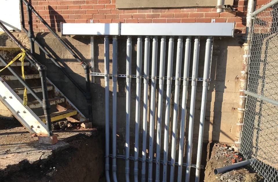 A brick wall with a bunch of metal pipes coming out of it