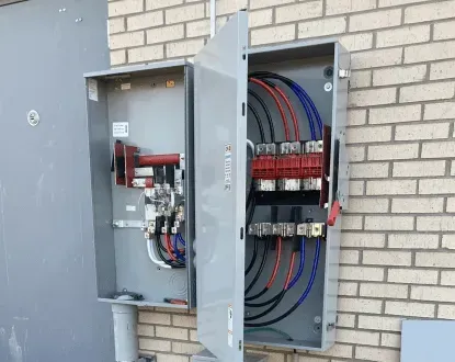 A large electrical box is sitting on a brick wall.