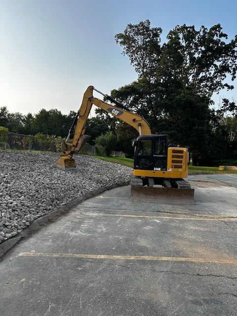 A patio with a couch , table , and umbrella in a garden.