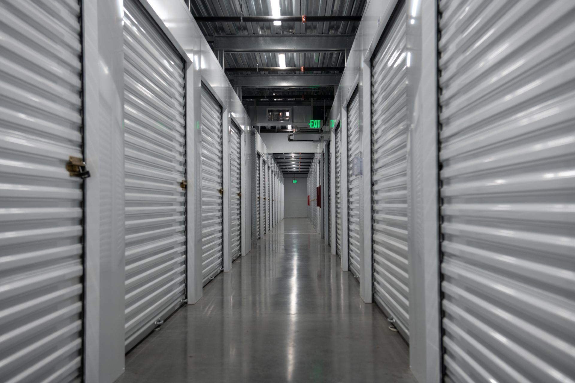 Indoor self storage hallway lined with white metal unit doors and a polished concrete floor