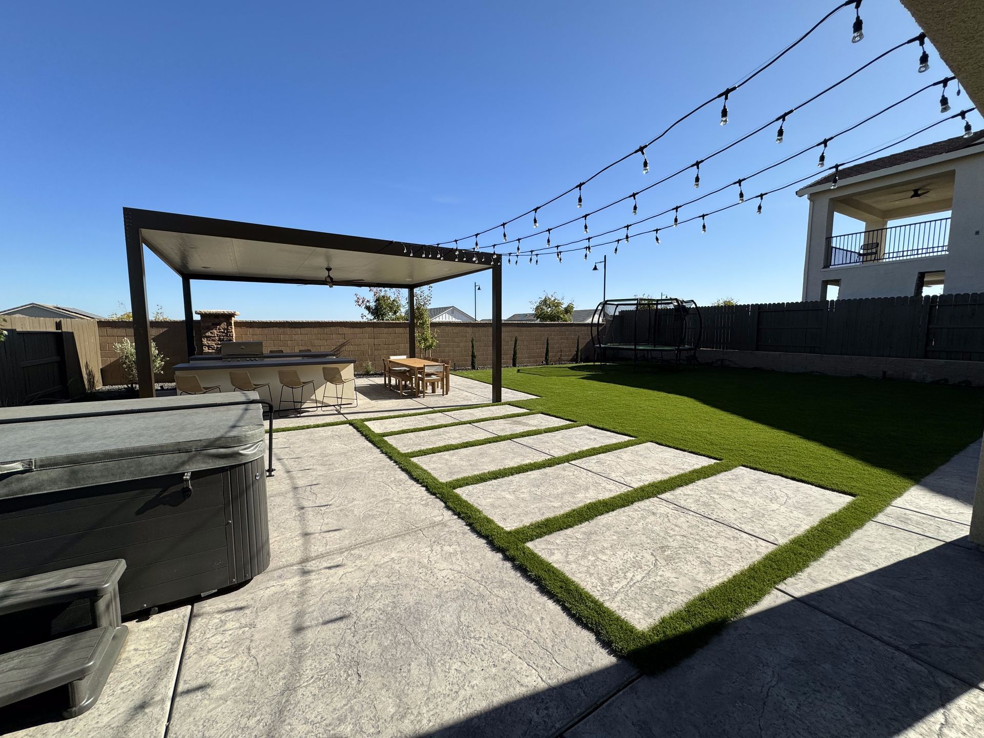 A backyard with a hot tub and a pergola.