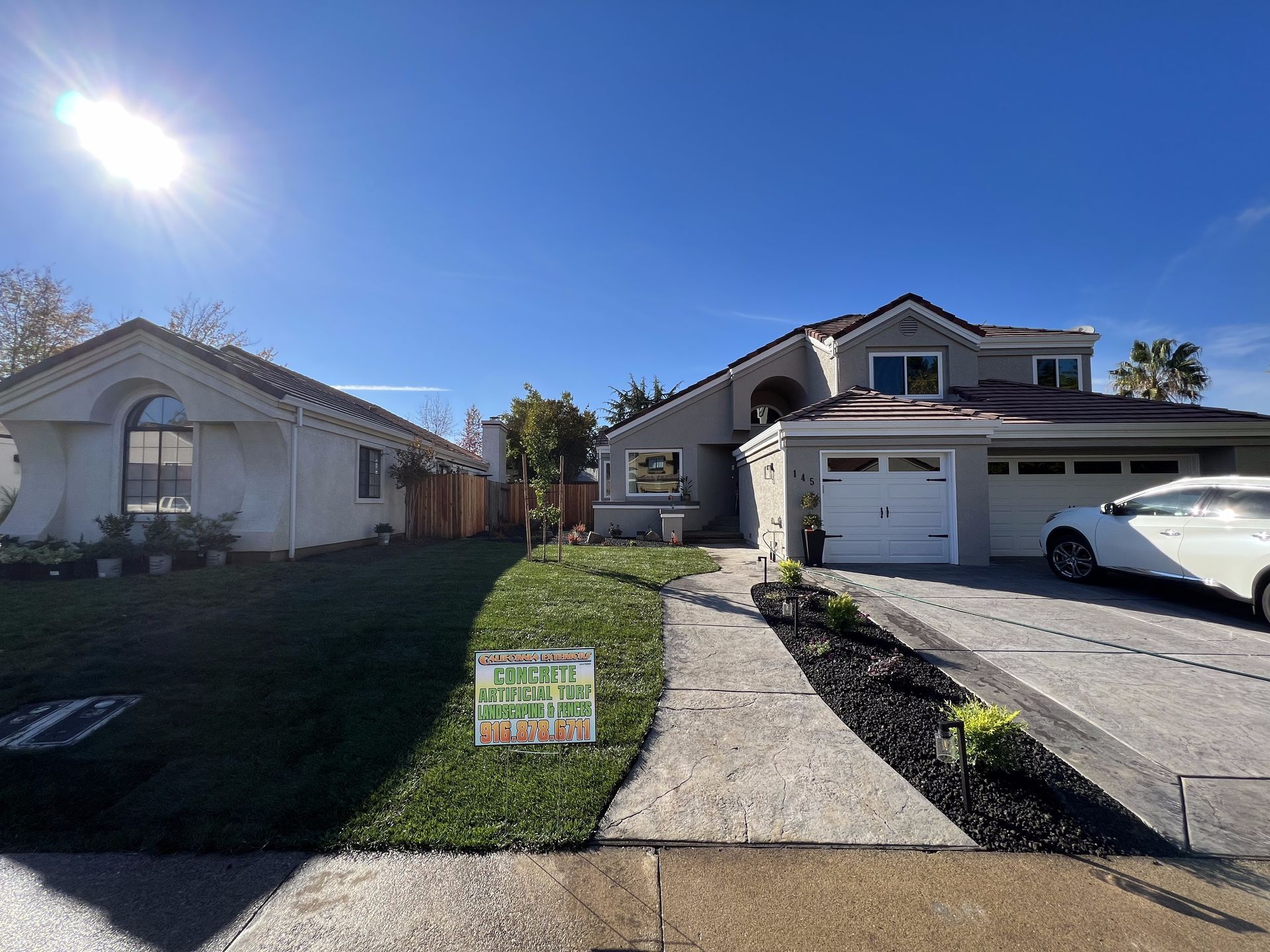 A white car is parked in front of a house.