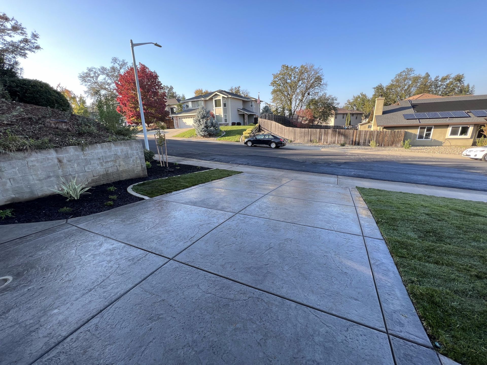 A car is driving down a residential street next to a sidewalk.