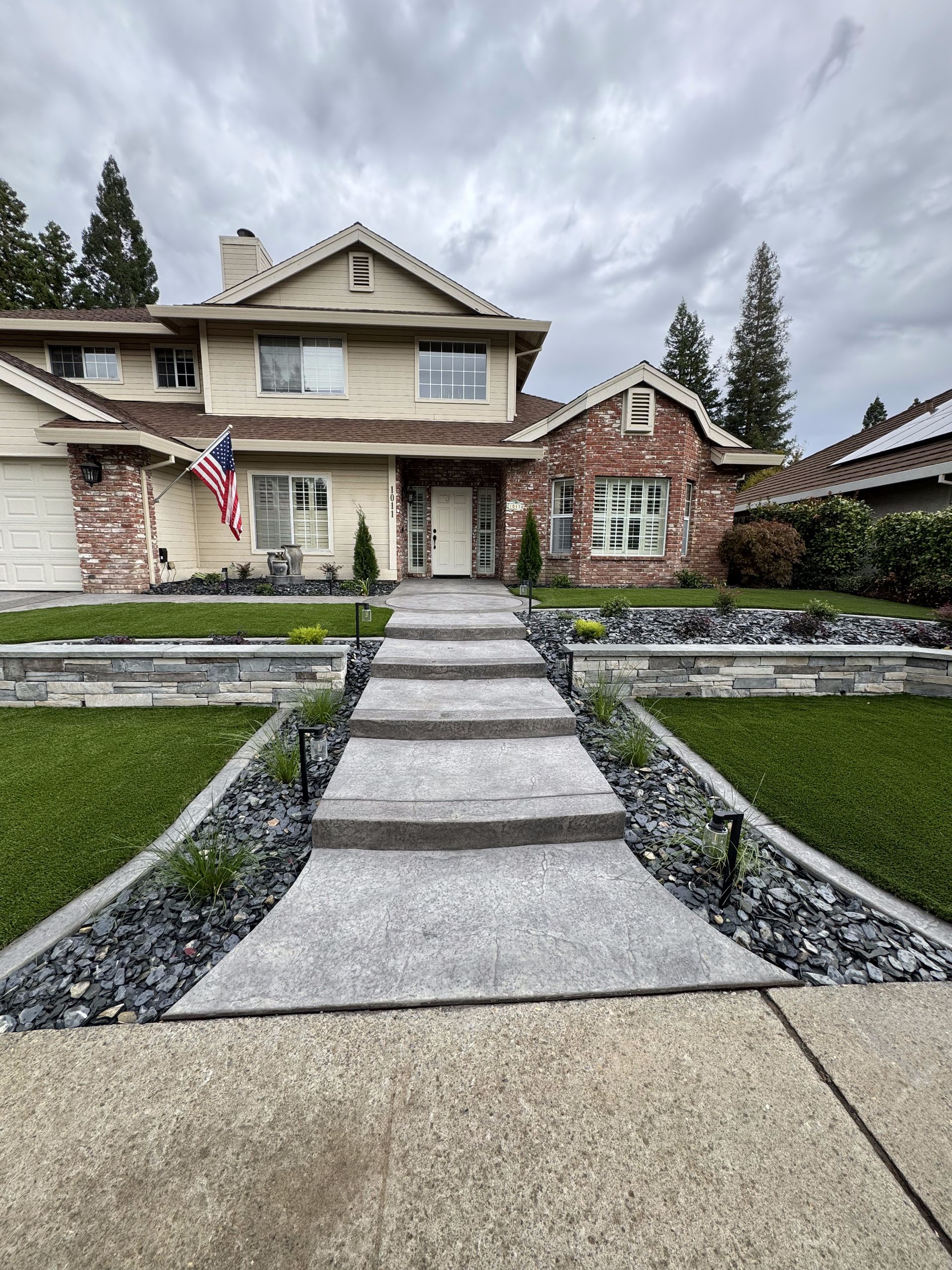A large house with a concrete walkway leading to it.