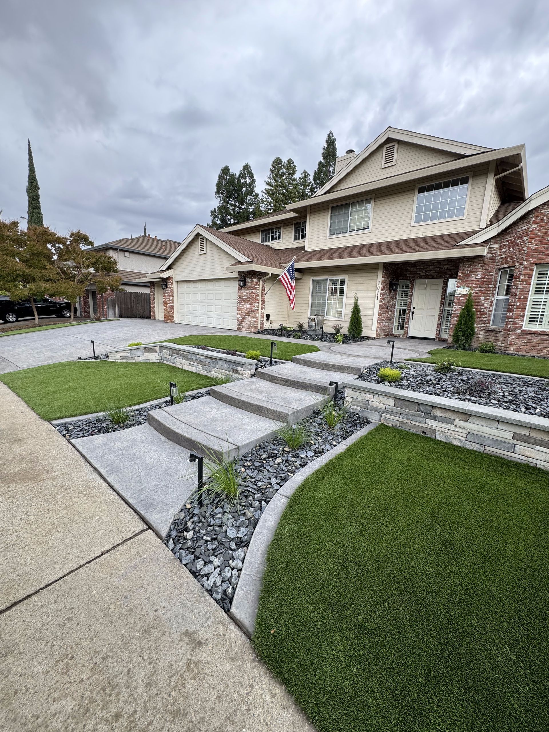 A large house with a lot of grass and rocks in front of it.