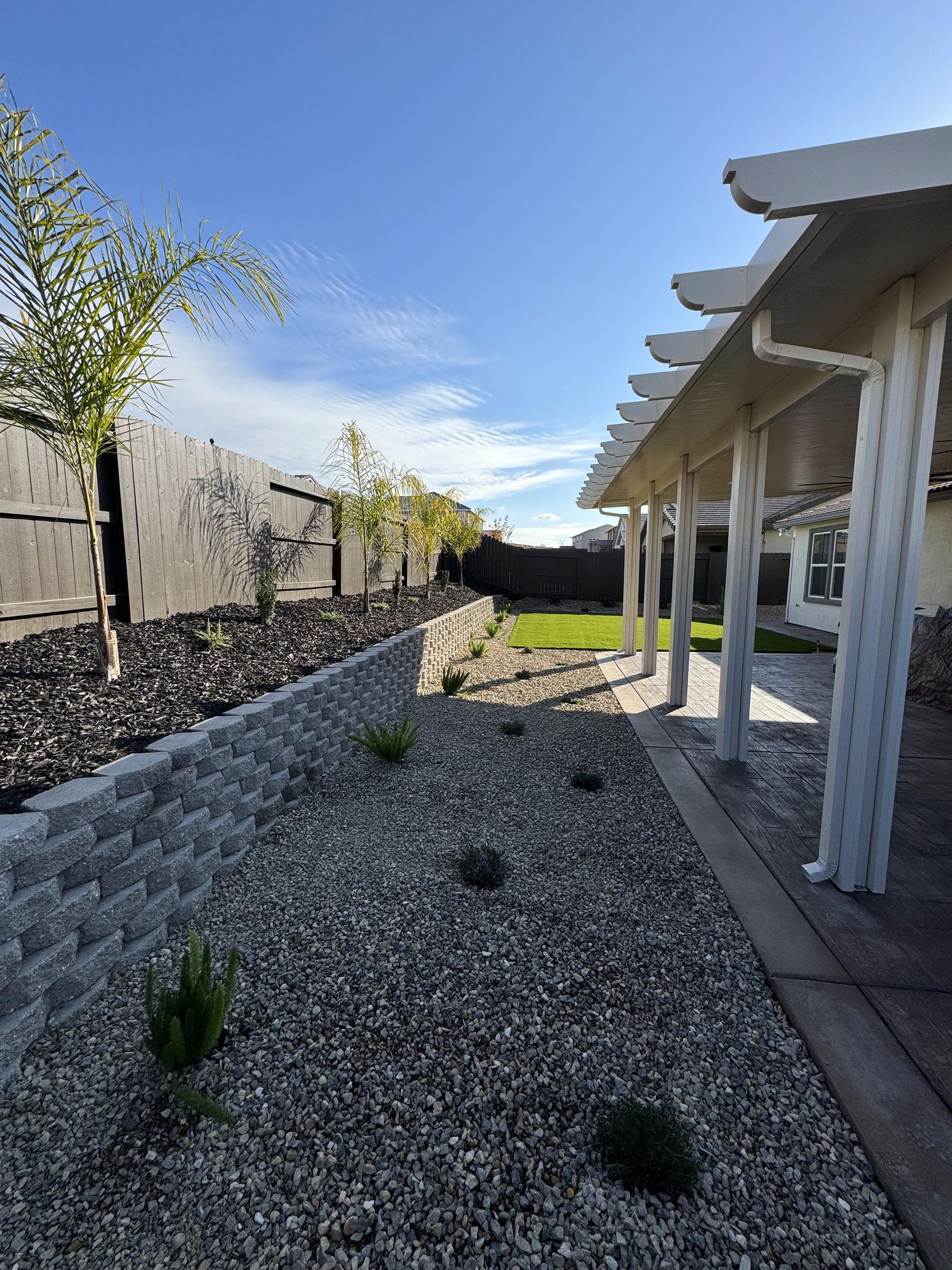 A walkway leading to a house with a pergola and gravel.