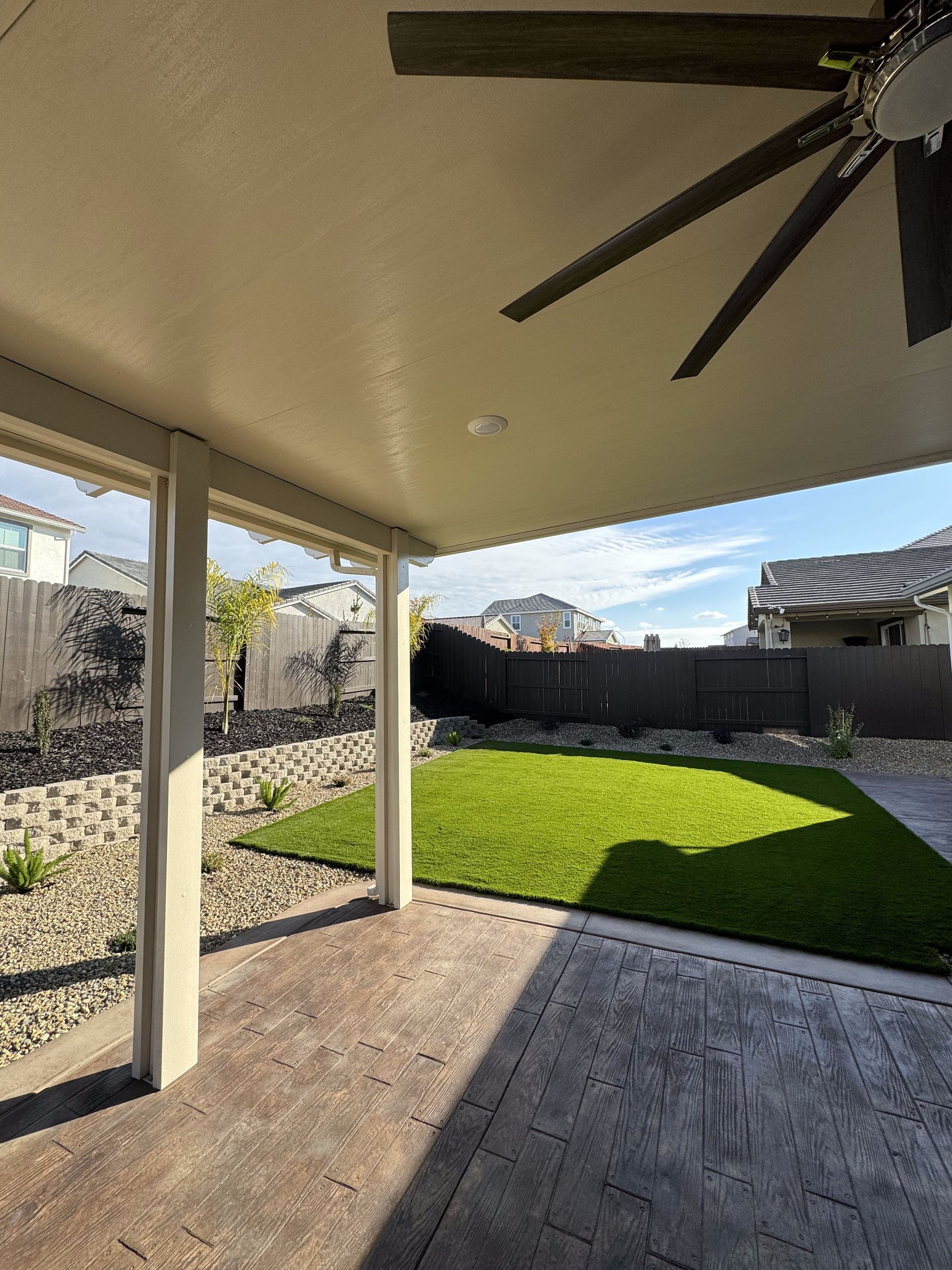 There is a ceiling fan hanging from the ceiling of the patio.