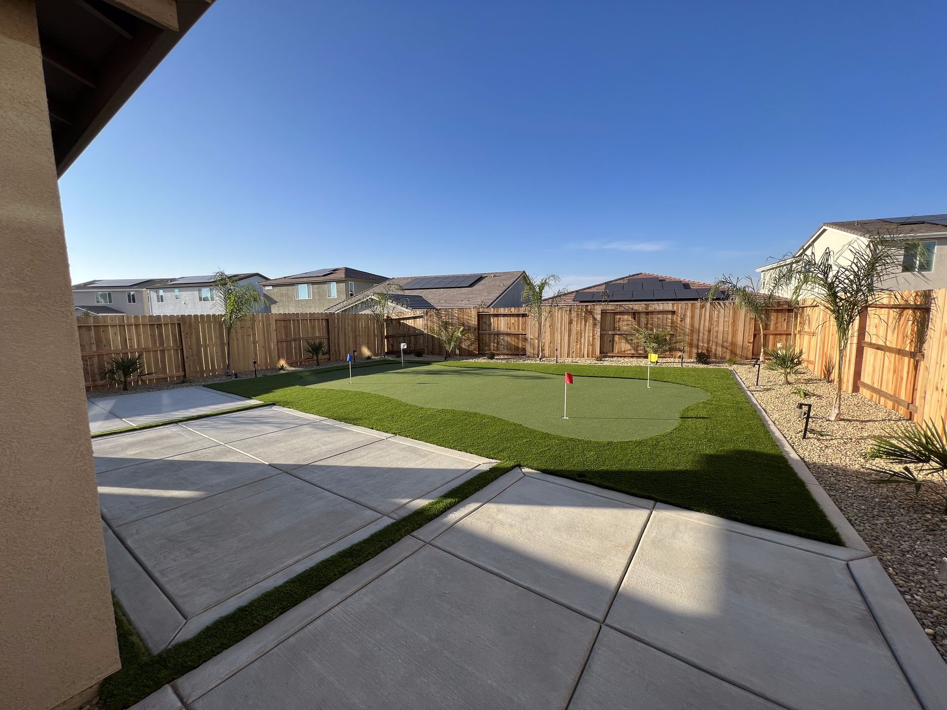 There is a putting green in the backyard of a house.