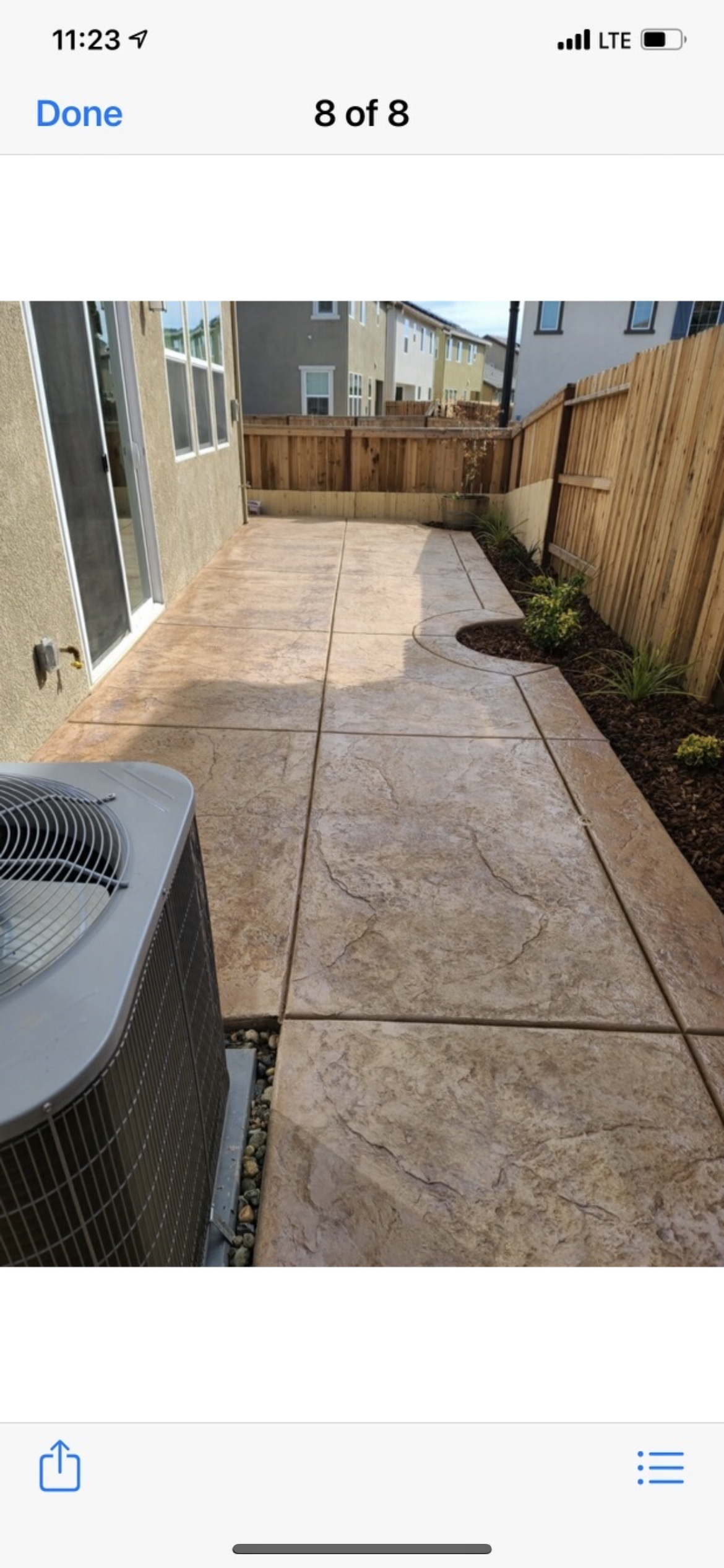 A picture of a patio with a fence and a concrete walkway.