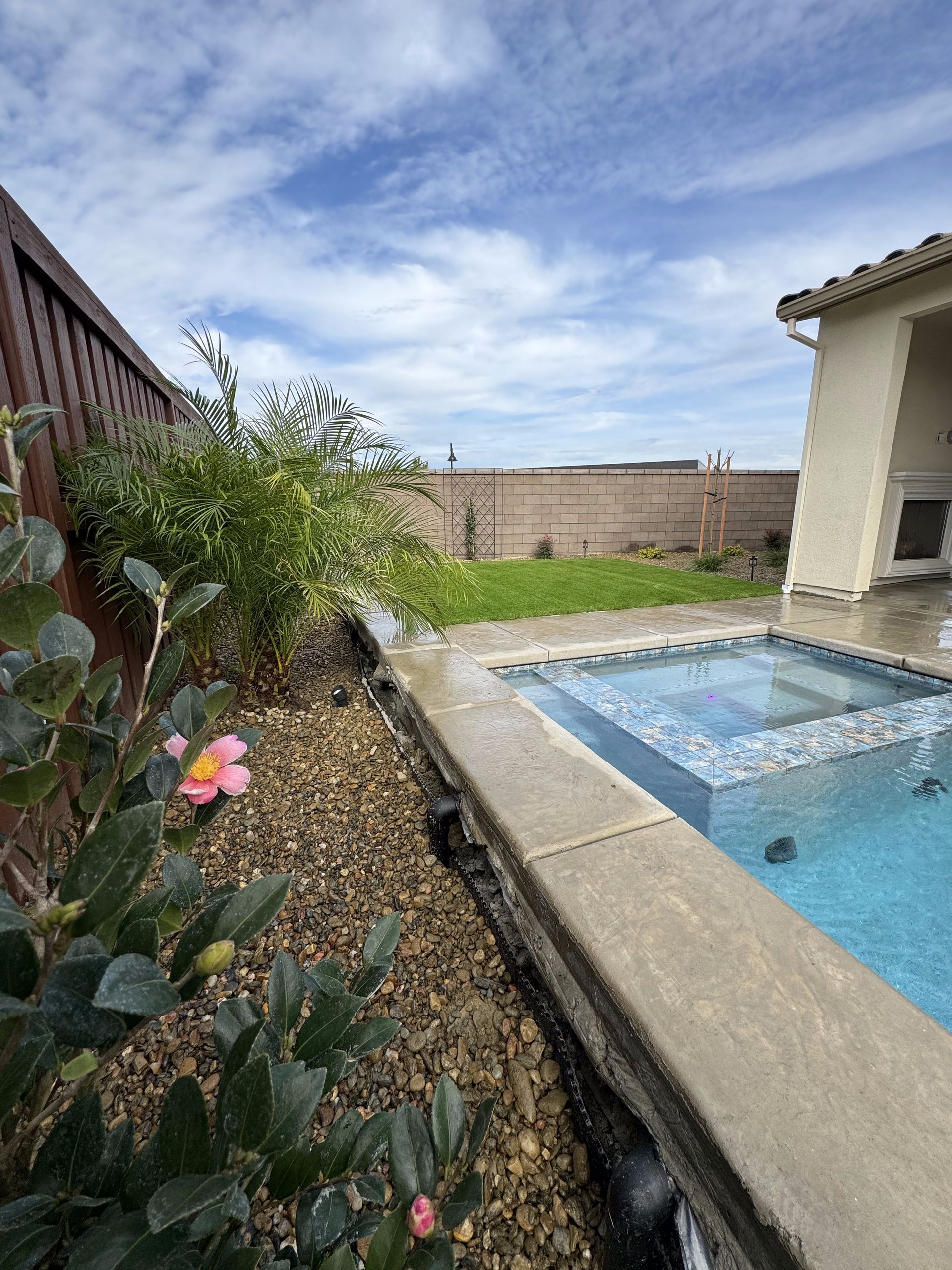 A swimming pool with a hot tub in the backyard of a house.