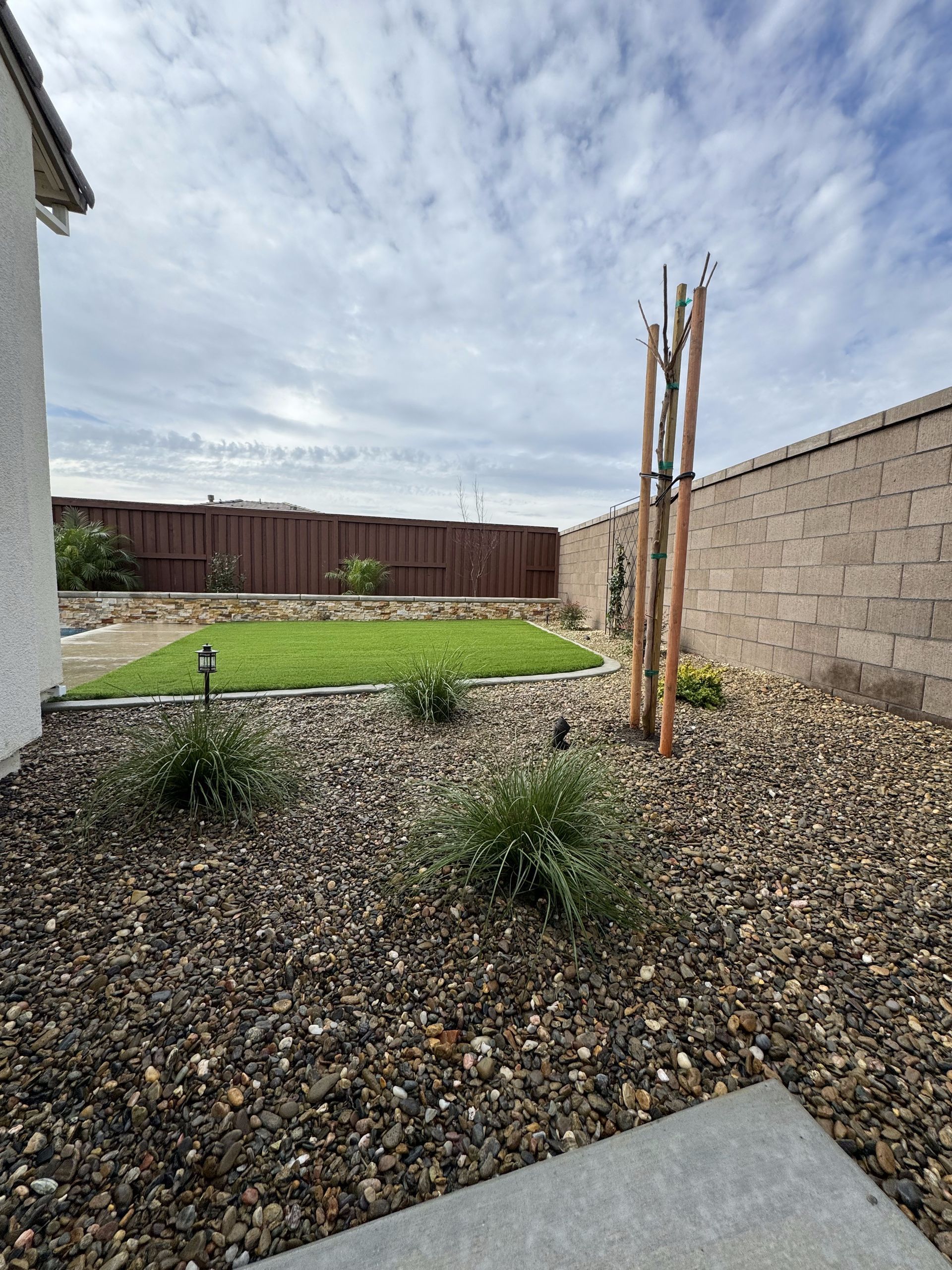 A backyard with a fence and a lot of gravel.
